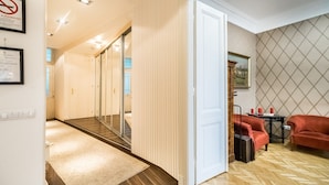 A hotel room with a wooden floor, a white door, a red sofa, and a small table with a red candle. - Magas 5 Apartment (Budapest)