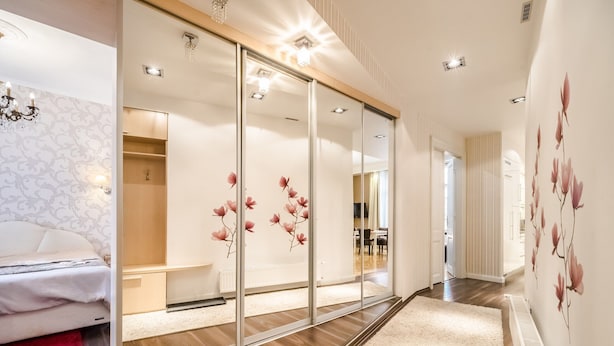 A modern hotel room with a large mirror, wooden flooring, a bed, a red rug, and a floral wall design. - Magas 5 Apartment (Budapest)
