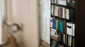 A bookshelf filled with books in a room with a door and a white wall. - Molnar 21 Apartment (Budapest)