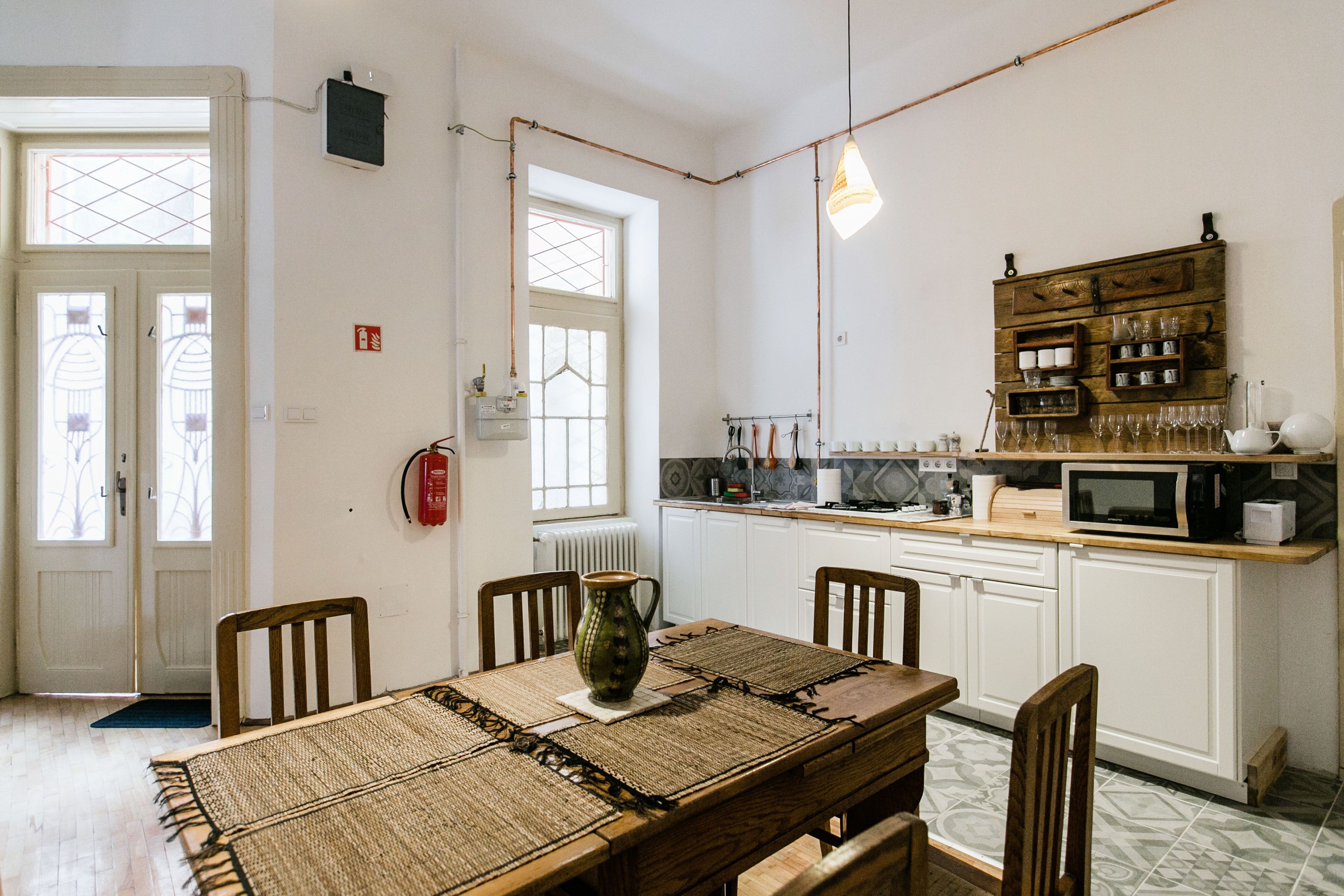 A kitchen with white cabinets, a wooden dining table, and a hanging light fixture.