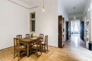 Un comedor con una mesa y sillas de madera, una ventana y una estantería.