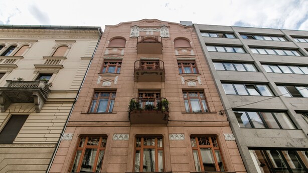 A multi-story building with a pink facade, large windows, and a central balcony with plants. - Molnar 21 Apartment (Budapest)