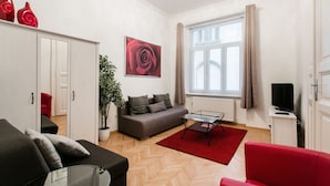 A modern living room with a sofa, red armchair, and a glass coffee table. - Nagy Diofa 18 Apartment I. (Budapest)