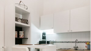 A modern kitchen with white cabinets, a stainless steel sink, and a bar stool. - Nagy Diofa 18 Apartment II. (Budapest)