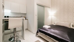 A compact bedroom with a bed, a small kitchenette, and a bathroom. - Nagy Diofa 18 Apartment II. (Budapest)