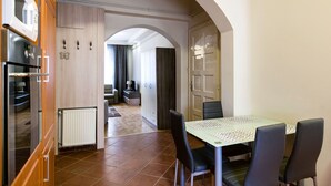A modern kitchen with an oven, microwave, and built-in cabinets. There is a dining area with a table and chairs. - Nagymezo 33 Apartment (Budapest)