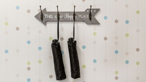 A wall with a sign that reads "THIS IS MY HAPPY PLACE" and two black bags hanging from it. - Nyar 7 Apartment (Budapest)