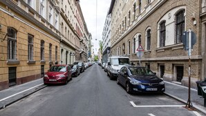 A narrow urban street lined with historic buildings, parked cars, and a visible traffic sign. - Nyar 7 Apartment (Budapest)