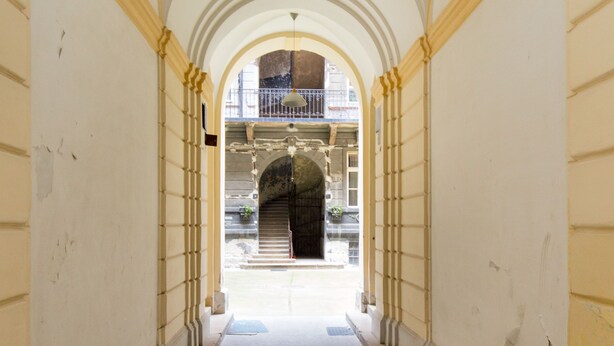 A corridor with arches and a view into a building with a balcony. - O 40 Apartment (Budapest)