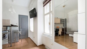 A modern kitchen with a built-in oven, a microwave, and a sink. There is a window with a view of the outside, and a mirror on the wall. - O 40 Apartment (Budapest)