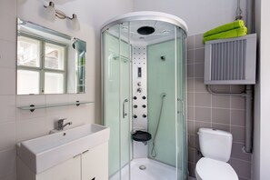 A modern bathroom with a glass-enclosed shower, a white sink, and a toilet. - O 40 Apartment (Budapest)