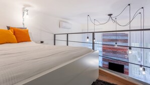 A modern bedroom with a large bed, a glass partition, and a city view. - Oktober 6 6 Apartment (Budapest)