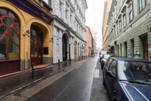 A street with parked cars, a building with a sign reading "Panlag," and a yellow awning. - Paulay 7 Apartment I. (Budapest)