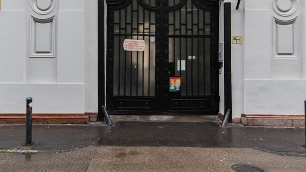Un edificio blanco con una verja negra, columnas y ventanas en arco.
