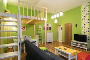Una habitación con literas, un escritorio, una silla, un televisor y una estantería.