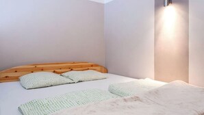 A bedroom with a wooden headboard, a bed with patterned bedding, and a wall-mounted light fixture. - Rakoczi 60 Apartment (Budapest)