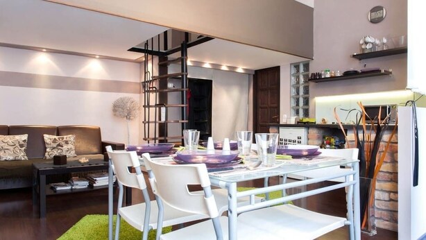 A modern living room with a dining area, a staircase, and a kitchen. - Rakoczi 60 Apartment (Budapest)