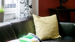 A living room with a leather sofa, a patterned curtain, a wall-mounted deer head decoration, and a small table with a fan. - Revay 2 Apartment (Budapest)