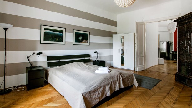 A bedroom with a bed, bedside tables, a lamp, and a wardrobe. - Revay 2 Apartment (Budapest)