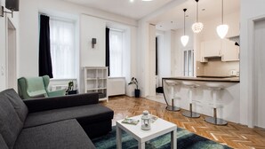 Ein modernes Wohnzimmer mit einer Couch, einem Couchtisch und einer Küchenzeile mit Barhocker.