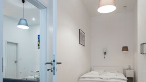 Ein Schlafzimmer mit einem Bett, einem Nachttisch, einer Stehlampe und einer Tür zu einem anderen Raum.