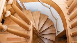Una escalera en espiral de madera con barandilla de cuerda y patrón de suelo en espiga.