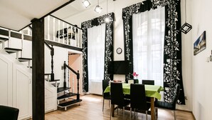 Un coin repas avec une table dressée pour quatre personnes, un escalier et une vue sur le salon.