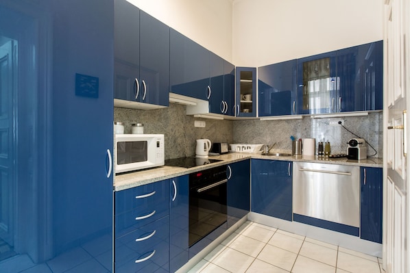 A modern kitchen with blue cabinets, a microwave, a toaster, and a dishwasher.