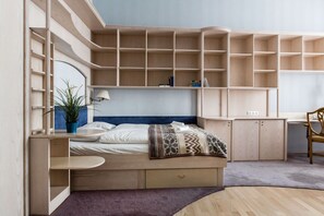 A bedroom with a bed, built-in shelving, a desk, and a chair.