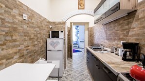 A compact kitchen with a microwave, refrigerator, and coffee maker. - Vorosmarty 73 Apartment (Budapest)