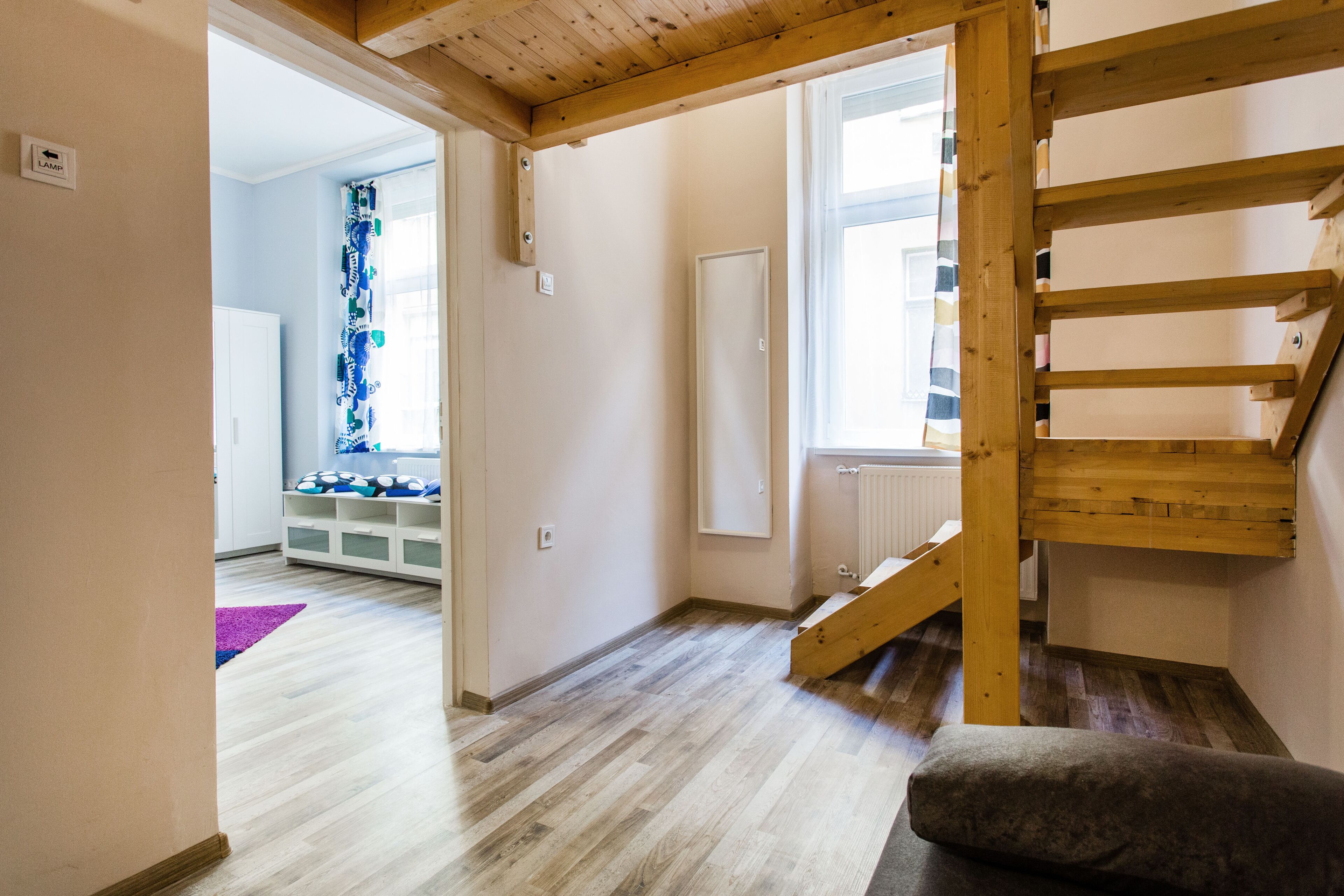 Eine Treppe mit hölzernen Geländern führt zu einer oberen Etage. Eine weiße Tür ist seitlich der Treppe zu sehen.