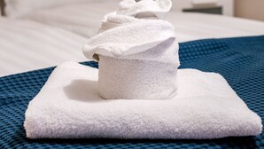 A neatly made bed with a folded white towel on a blue textured bedspread. - Vorosmarty 73 Apartment (Budapest)