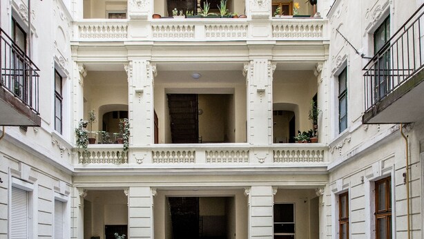A multi-story building with a central courtyard, balconies with plants, and a grand entrance. - Vorosmarty 73 Apartment (Budapest)
