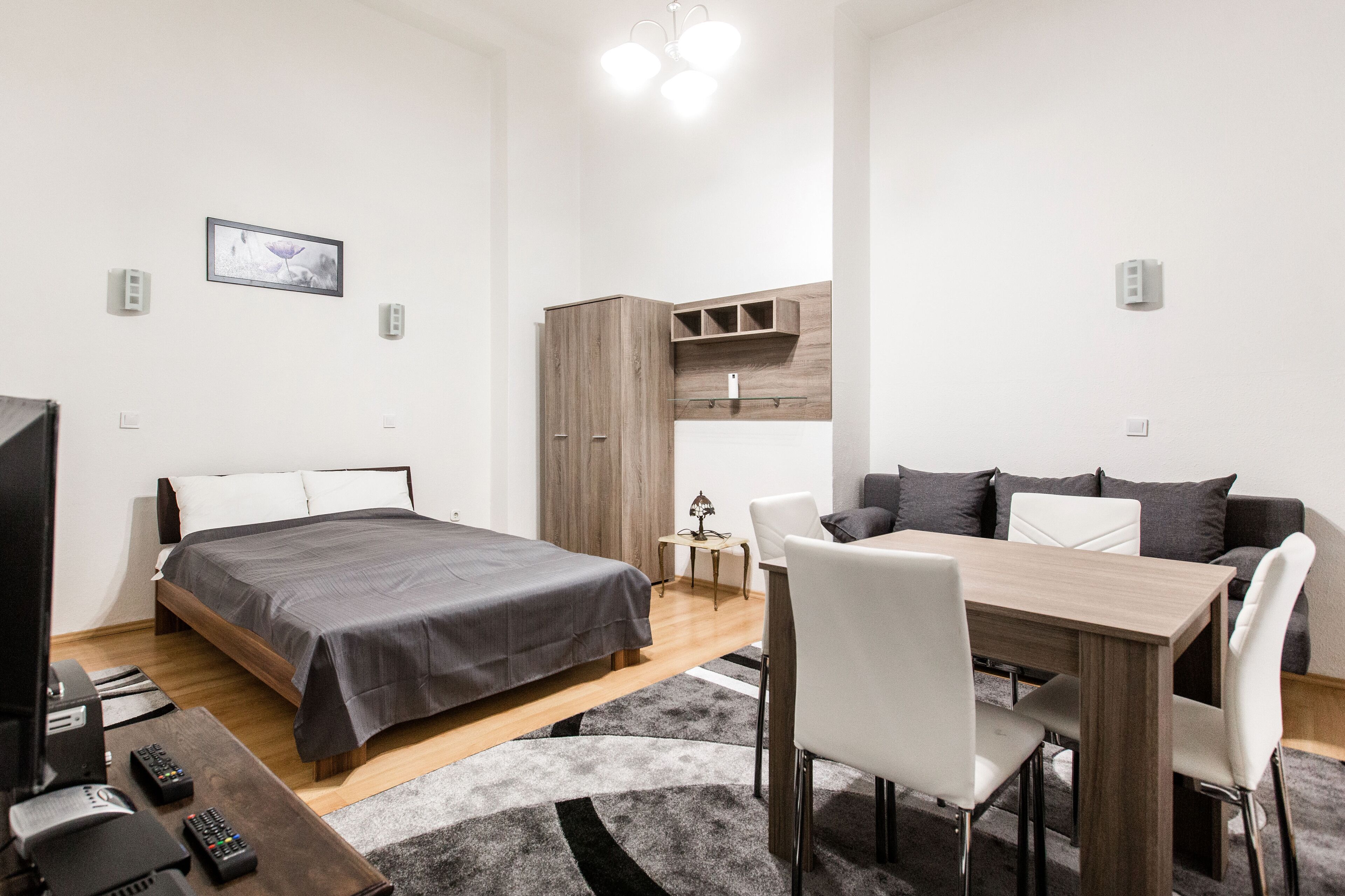 A modern bedroom with a bed, bedside table, and a desk with chairs.
