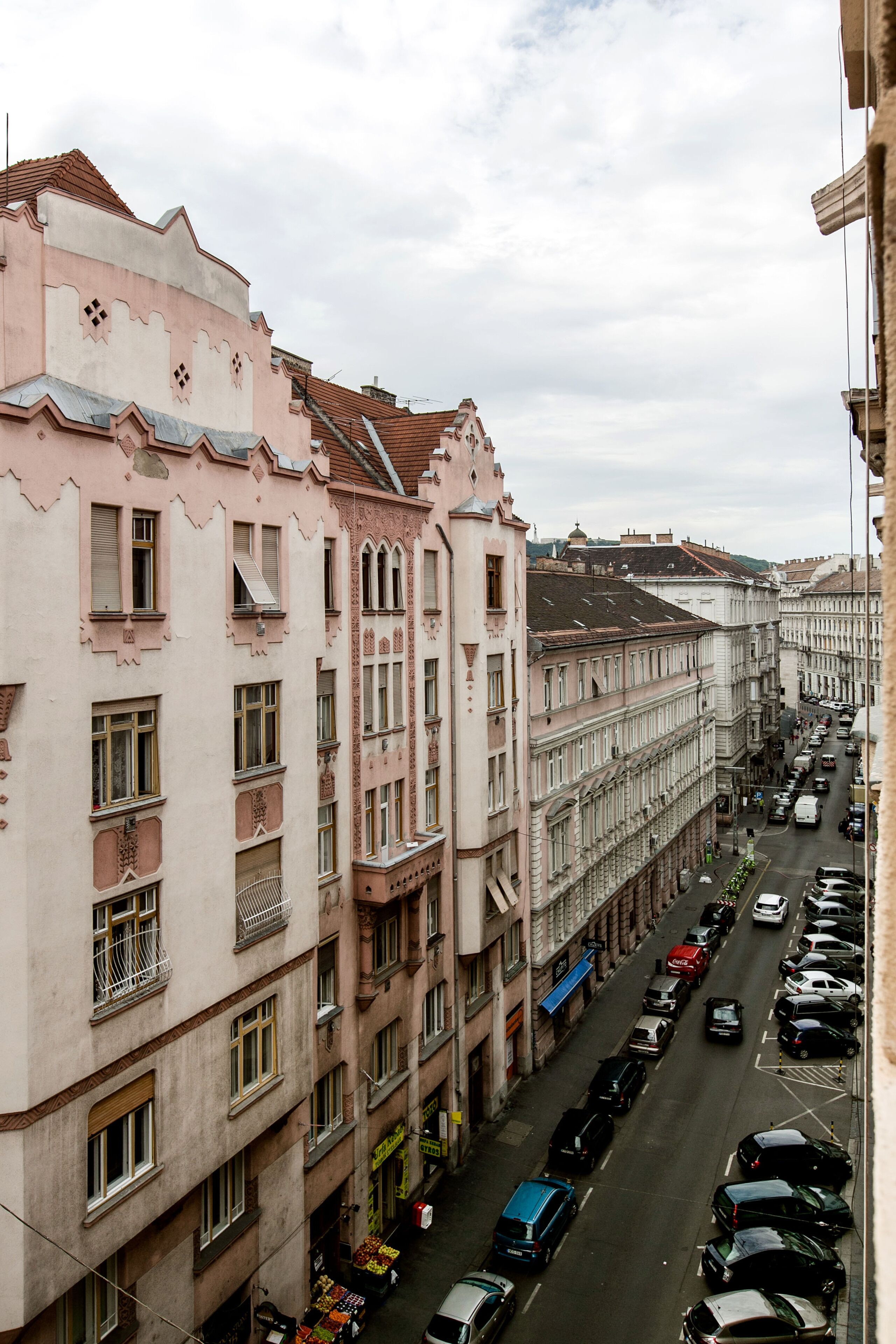 A street view of a row of buildings with balconies and a clear sky.