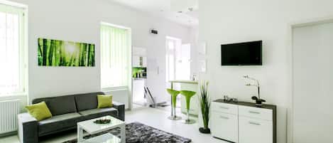 A modern living room with a grey sofa, a coffee table, and a TV mounted on the wall.