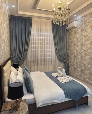 A bedroom with a large bed, draped curtains, a chandelier, and a patterned wallpaper. - Art Apart Hotel (Tashkent)