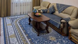 A living room with a sofa, a coffee table, a chandelier, and a patterned rug. - Art Apart Hotel (Tashkent)