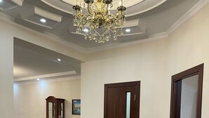 A spacious hallway with a large, ornate chandelier, a wooden door, and a dining area with a table and chairs. - Art Apart Hotel (Tashkent)