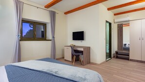 Een slaapkamer met een bed, een bureau, een stoel, een televisie en een kledingkast.