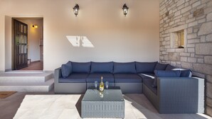 Een moderne woonkamer met een hoekbank, een glazen salontafel en een stenen wand.