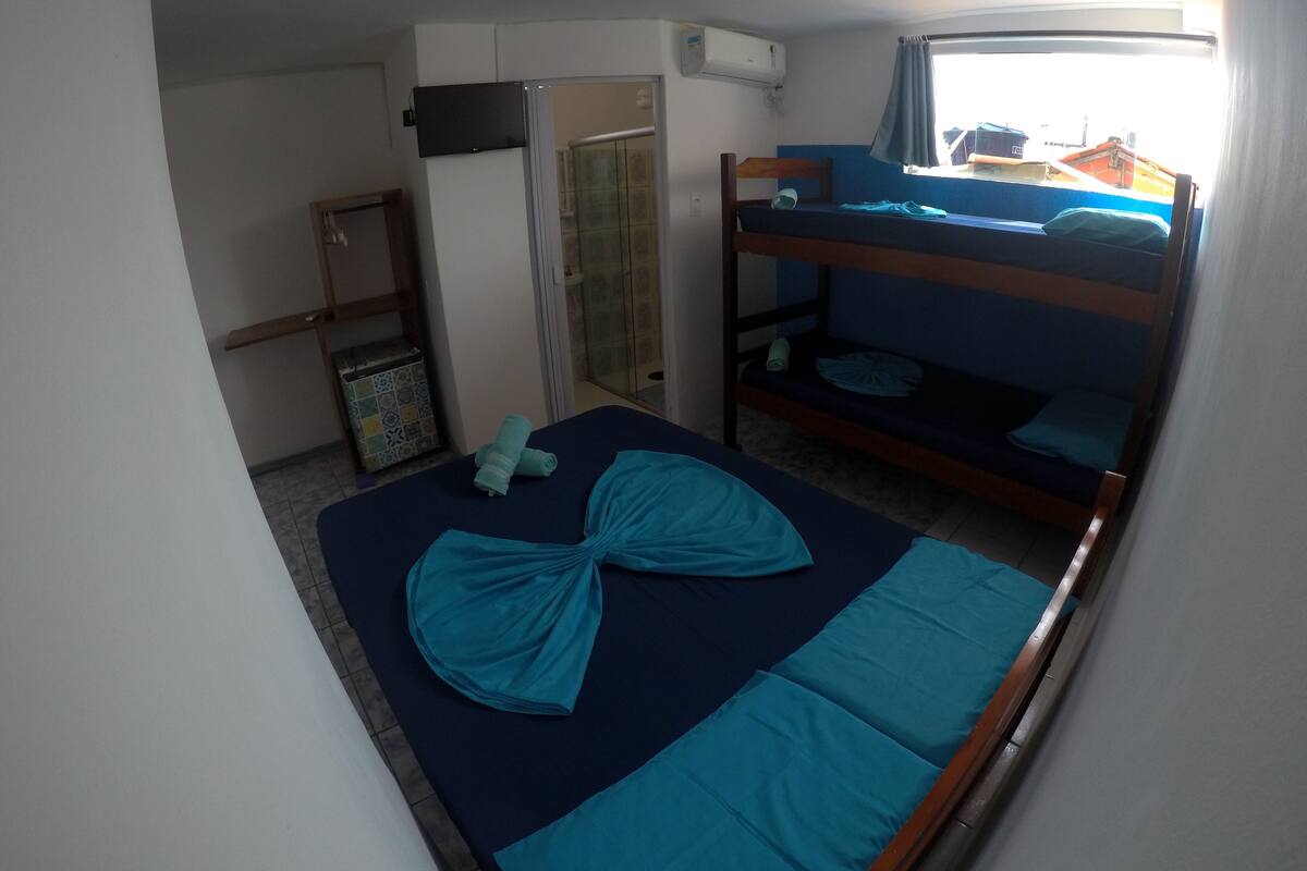 A bunk bed room with a blue mattress, a small table, and a window with curtains.