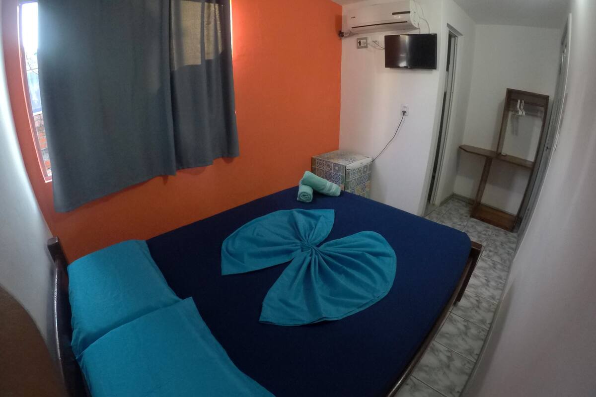 A room with a bed, a TV, and a window with curtains.