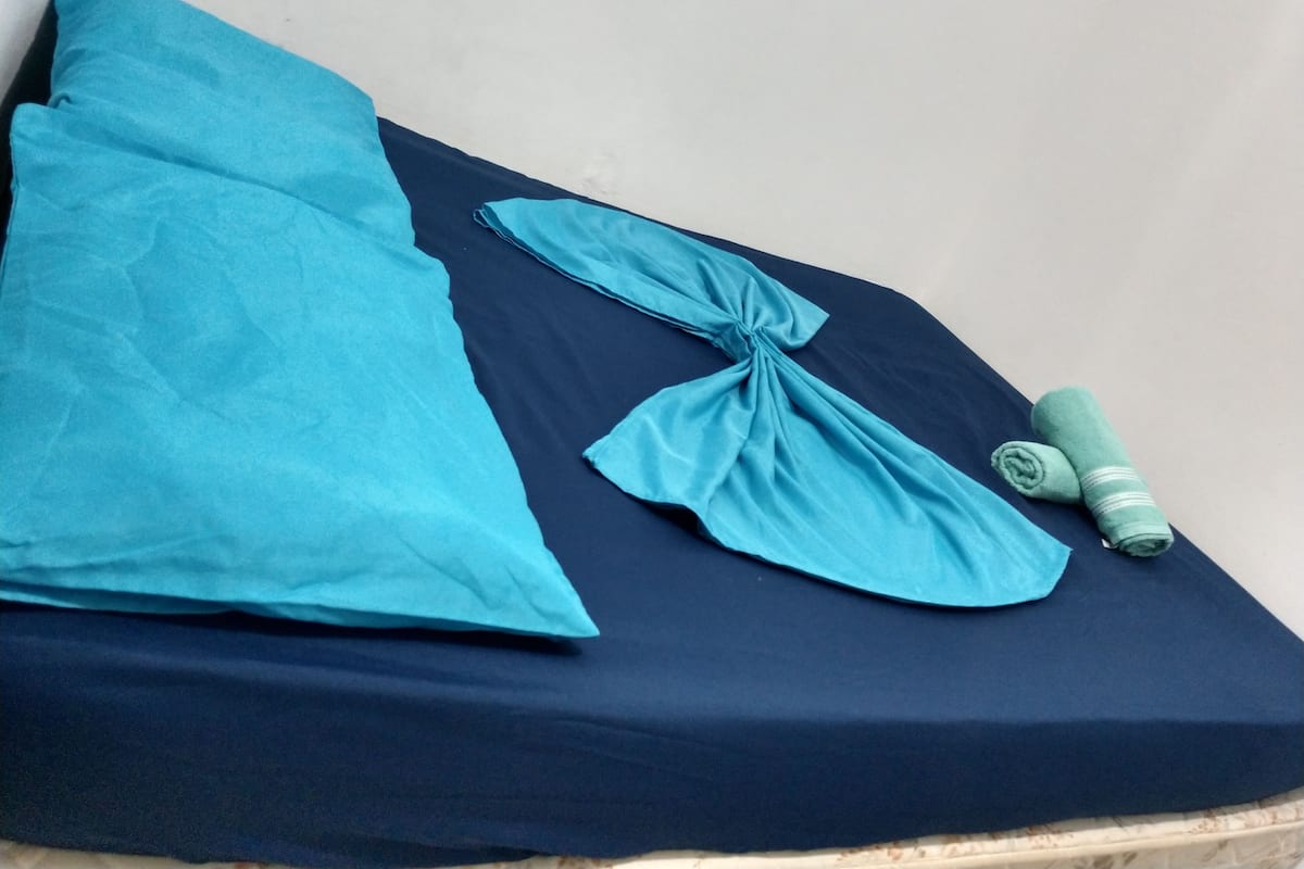 A bed with a dark blue mattress and a light blue pillow.