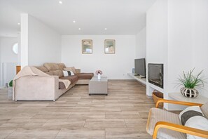 A modern living room with a sofa, a coffee table, a TV, and a plant. - Villa Sunrise · Villa Sunrise ❤️ Seaviews ❤️ big, modern, AC (San Jaime Mediterráneo)