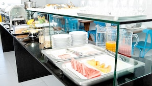 Un buffet proposant une variété de plats et de boissons, notamment des fruits, des viandes et des jus de fruits.