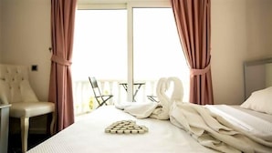 A hotel room with a bed, a chair, a table, and a window with curtains.