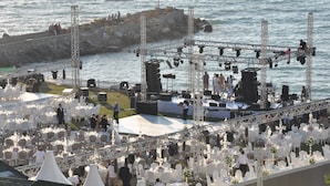 A wedding reception with a stage and seating area by the water.
