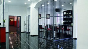 A modern hotel lobby with a black-tiled floor, a reception desk, and a seating area enclosed by metal bars. - Alcatraz am Japanischen Garten (Kaiserslautern)