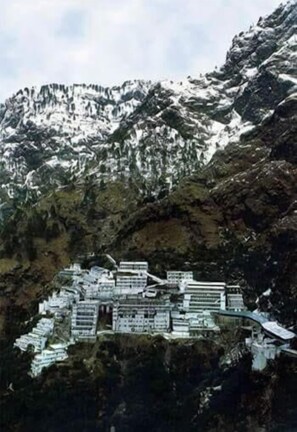 A mountainous area with a cluster of buildings. - Hotel Aashirwad (Reasi)